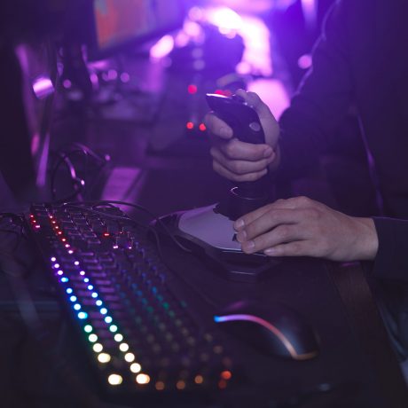 Close up of unrecognizable man using racing joystick while playing video games in dark room, copy space